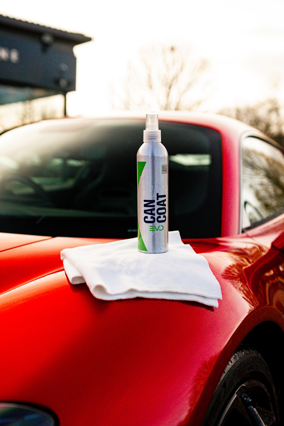 Kleinsprühflasche und Mikrofasertuch auf roter Autokarosserie